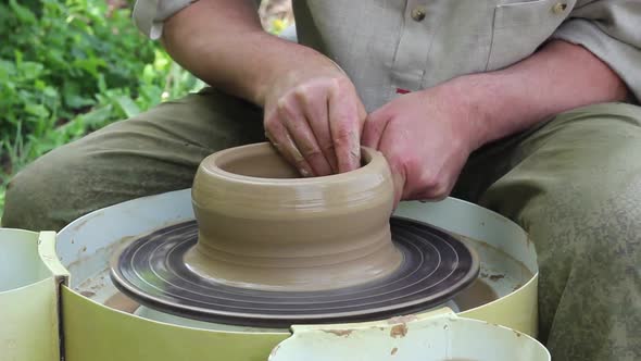 Male Potter of Caucasian Ethnicity in Working Uniform Makes a Clay Pot Closeup alt