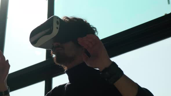 Man with VR Glasses Wants to Look Around and Tries to Touch Something with Hands alt