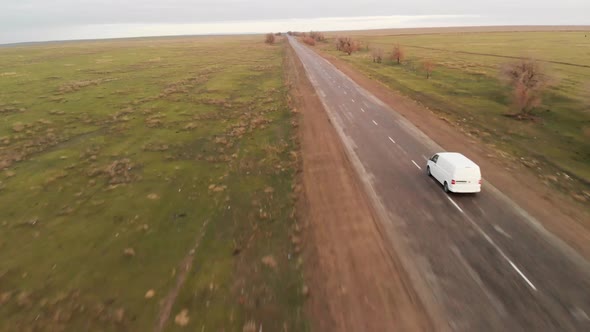 Aerial View White Car Travels at Spring Desert