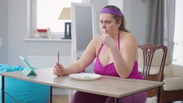 Depressed Overweight Woman Looking at Cucumber Slices in Plate Sighing alt