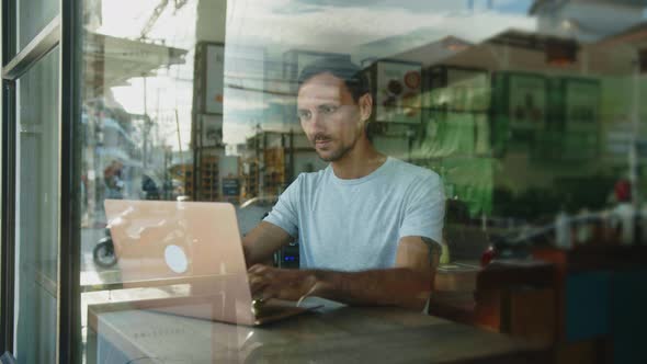 Digital Nomad Works on a Laptop in a Coffee Shop alt