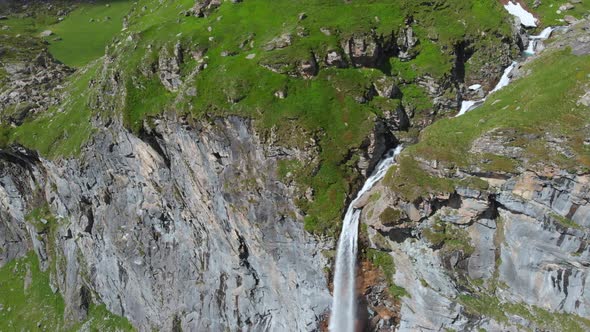 Aerial: drone flying over scenic waterfall and mountain stream on the italian Alps alt