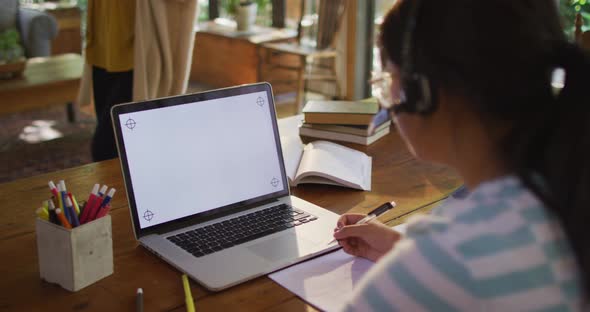 Asian woman sitting at table and using laptop with copy space, making video call alt
