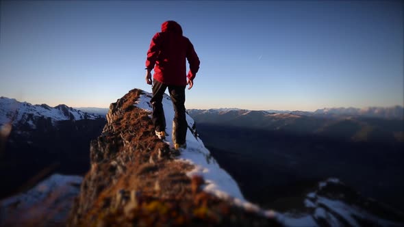 A man reaching the summit after climbing on a snow covered mountain. alt