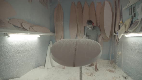 Surfboard Shaper Polishing Surfboard in Workshop alt