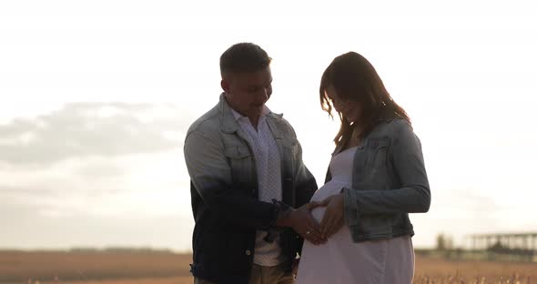 Portrait of Young Pregnant Couple in Field