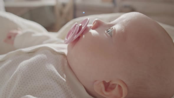 Little Baby with Pacifier Lying on Bed alt