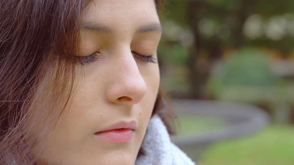 beautiful young woman with closed eyes,opening her blue eyes and looking-outdoor alt