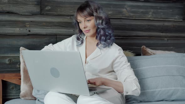 Attractive Young Lady Using Laptop Sitting in Bed at Home Alone Enjoying Social Media Online alt