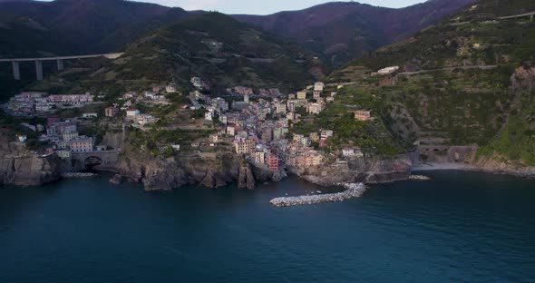 Colorful houses of coastal village hugs mountainside, Riomaggiore; drone alt