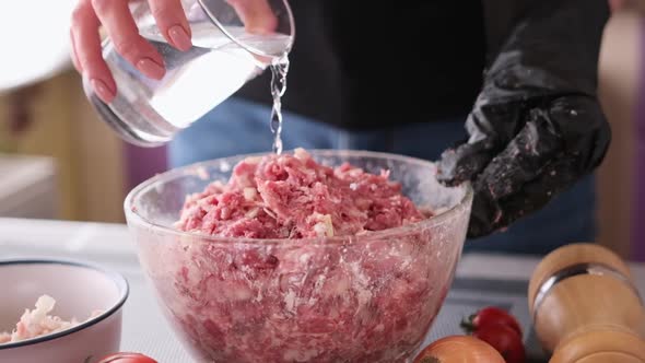 Adding Water to Minced Meat with Onion and Spices in a Glass Bowl Making Cutlets alt