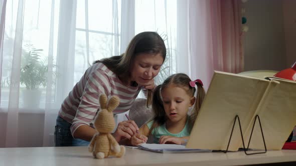 Mother And Daughter Doing Homework From School Together