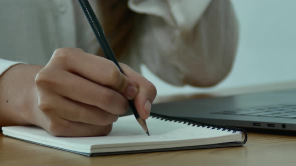 young smiling asian woman working on laptop while sitting in a living room at home. alt
