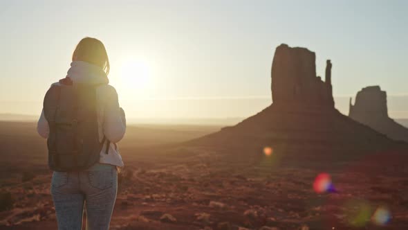 Woman Tourist in Desert Landscape at Sunrise Golden Sunbeams Flare Red Cliffs alt