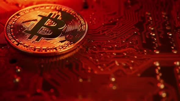 Golden coin with bitcoin symbol on electronic circuits in a computer mainboard. alt