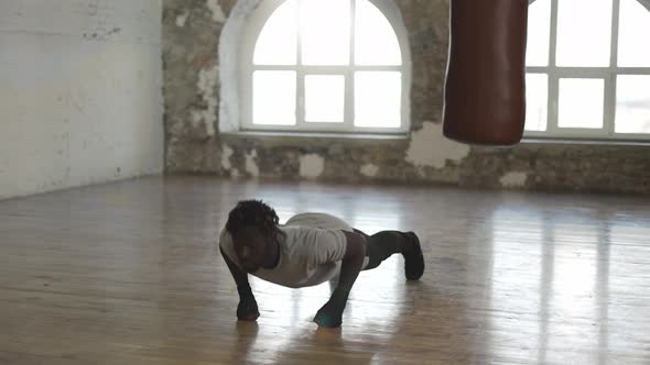 Boxer Doing Pushups on the Floor While Working Out in Old Light Building in Slowmo alt