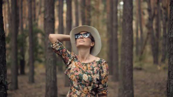Holiday Vacation Tourist Trip In Forest Warm Day. Active Woman In Hat Walking On Tree. alt