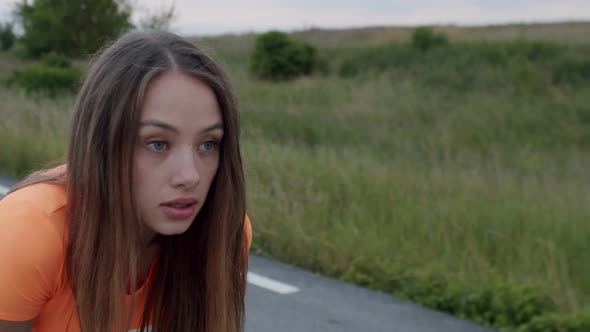 Close Portrait of Sporty Girl Takes a Breath During Workout on a Road at Nature alt