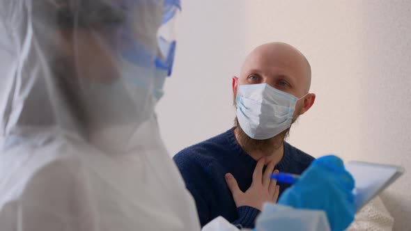 A Middleaged Man in a Mask Sits at the Doctor's Office and Complains of a Sore Throat and Headache alt
