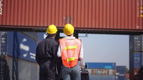Engineer and foreman team in hardhat and safety vest control loading containers box from cargo