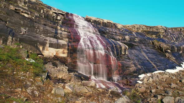 Aerial View Of Waterfall Cascading Down Red Coloured Rock Face At Hardangervidda National Park. Low alt