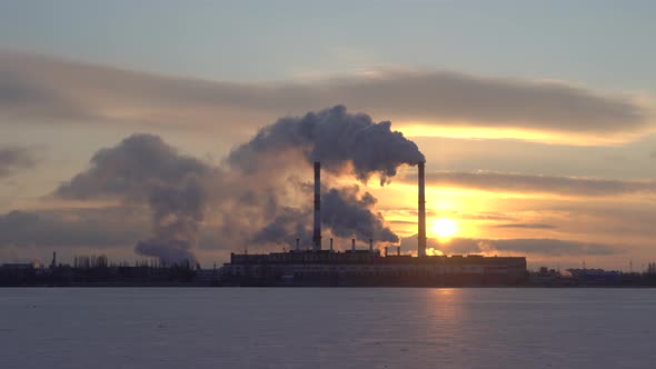 Industrial zone with factory chimneys producing smoke at sunrise alt