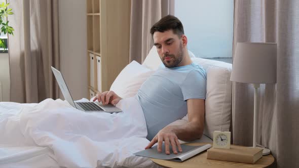 Man with Laptop Working in Bed at Home Bedroom