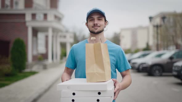 A Young and Energetic Delivery Man Carrying a Pizza and a Bag of Groceries alt