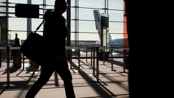 Air Travelers Passing Empty Airport Gates at Sunlit Terminal, Boarding Procedure alt