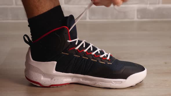 A Closeup of a Man's Hands Tying the White Laces of His Basketball Sneakers alt