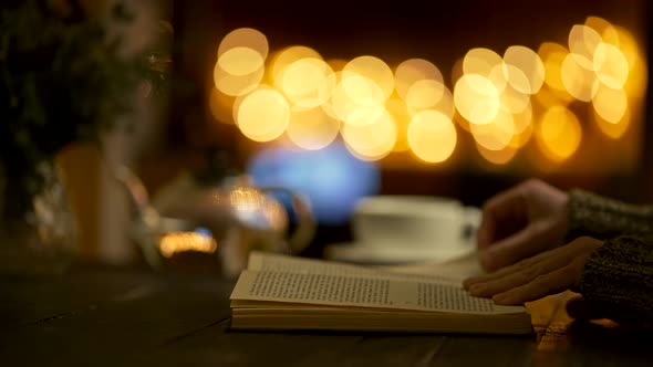 Woman Reading a Book Flipping Its Pages at Home in Evening. Teapot and a Tea Cup, Beautiful Round alt