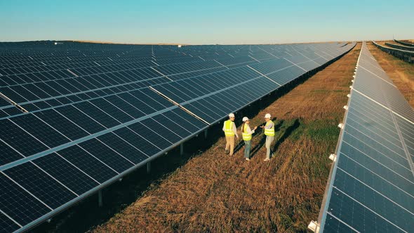 Workers in Uniform and Helmets Performing Inspection at Solar Farm alt