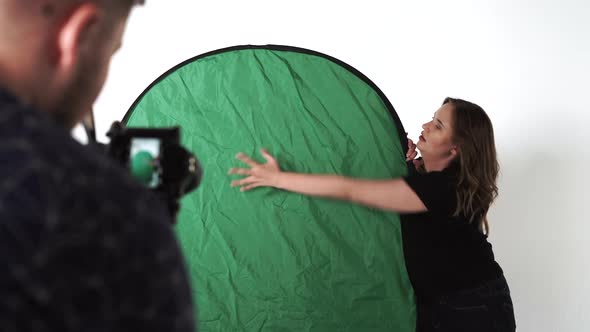 Studio Backstage Female Actress Make Hand Motion Standing on a Green Background