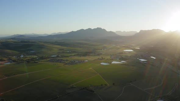 Sun rays sunrise lens flare over vineyard landscape, mountains aerial, Stellenbosch, Longlands alt