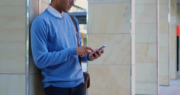 Man using mobile phone against pillar alt