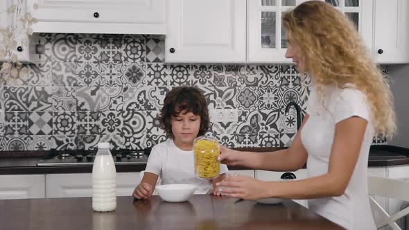 Boy Waiting Eagerly For his Healthy Breakfast with Flakes and Milk which Preparing His Caring Mother alt
