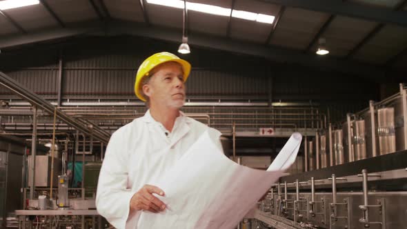 Worker looking at blue print while examining alt