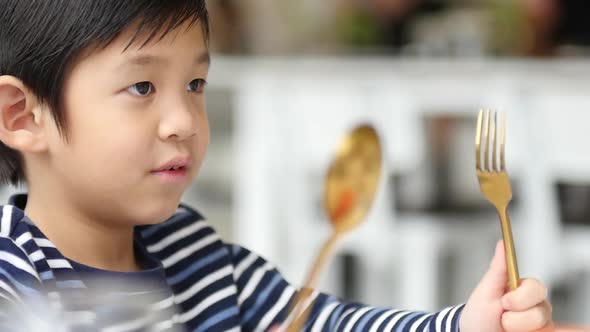 Cute Asian Child Holding A Spoon And Fork With Empty White Plate In ...