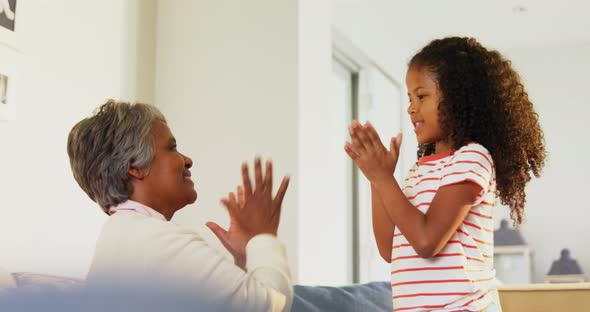 Granddaughter and grandmother playing clapping games in living room alt