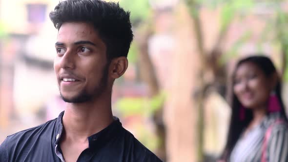 Boy standing in foreground shying and smiling with woman in background, focus rack, cute romantic co alt