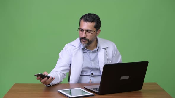Handsome Persian Bearded Man Doctor Multitasking at Work