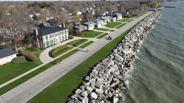 Motorcycles leading runners down residential street along lake shoreline in the sunshine.