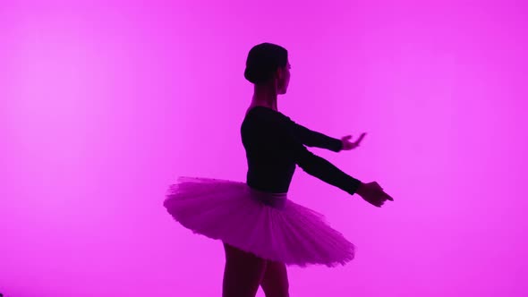 Professional Ballet Dancer Spinning Around in Pink Studio Wall with Violet Light alt
