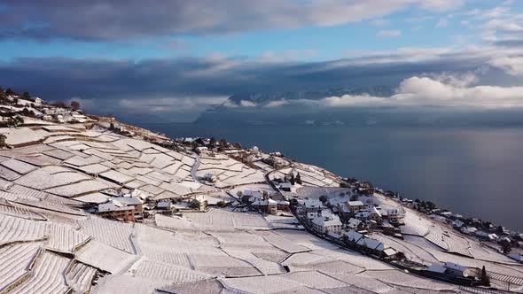 Aerial view over typical Swiss village in Lavaux vineyard covered by snowThe Alps and Lake Leman in alt