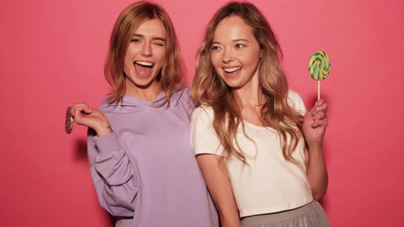 Two young beautiful smiling blond hipster girls in trendy summer clothes alt