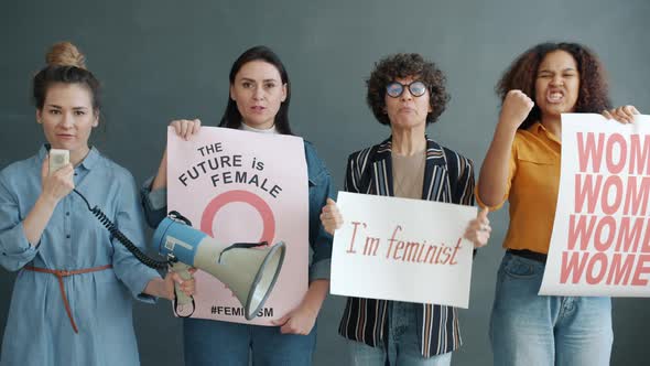 Diverse Group of Aggressive Women Fighting for Female Rights Screaming and Holding Banners on Grey alt