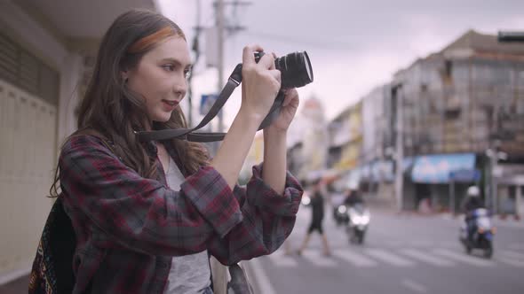 A beautiful woman tourist enjoys taking photos of the city view in Bangkok, Thailand. alt