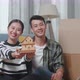 Young Asian Couple With Cardboard Boxes Smiling And Showing House Model To Camera In The New House - VideoHive Item for Sale