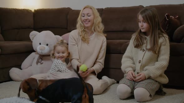 Mom with Daughter at Floor Play with Pets Dog Throw Ball for Dachshund Rbbro alt