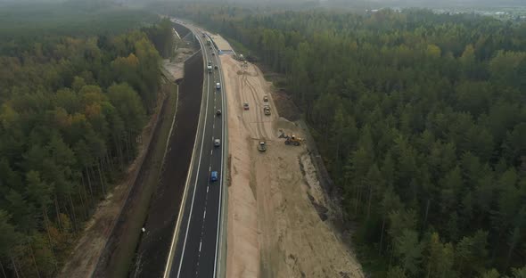 New Highway Road Construction Between Green Forest Aerial View at Sunrise alt